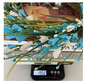 Decorative blue and white floral berry wreath being weighed on a digital scale showing 195.2g