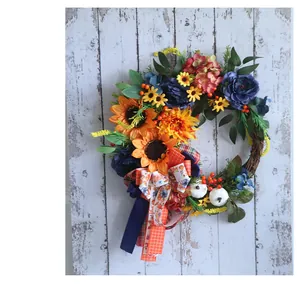 Rustic floral wreath with sunflowers, blue hydrangeas, and white pumpkins on a wooden wall.