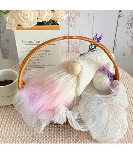 Handcrafted plush faceless gnome with pink gradient beard resting in a wicker basket.