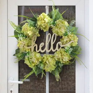 Artificial hydrangea floral wreath with hello wood sign hanging on a white door.