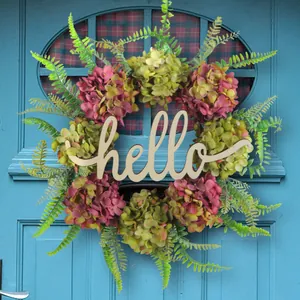 Beautiful artificial hydrangea floral wreath with a wooden hello sign on a blue door