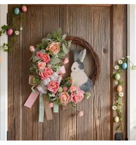 Detail eines Osterkranzes mit Hase und rosa Rosen an einer rustikalen Holztür