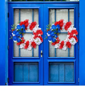 Detailed view of patriotic red white and blue artificial floral wreaths on blue door