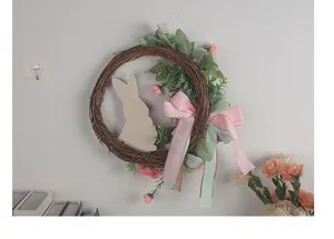 Detail eines handgefertigten Osterkranzes mit Holzhasen und Pastellbändern an der Wand