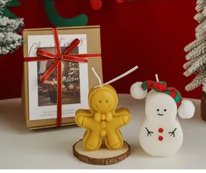 Detail view of gingerbread man and snowman scented candles in a festive Christmas gift box