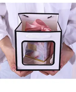 Close-up of white square kraft paper gift bag with window and pink ribbon box inside