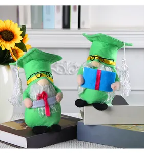 Due adorabili gnomi laureati in peluche verde con tocchi e nappe su sfondo di libri