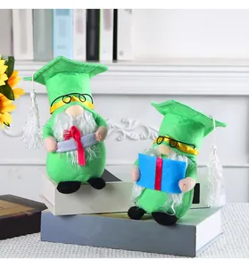 Dettaglio di due gnomi di laurea con cappelli verdi che tengono un diploma e un libro