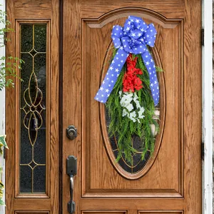 Corona de puerta patriótica del Día de la Independencia con flores rojas y lazo azul.