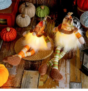 Close-up of glowing harvest gnomes with maple leaf hats and long striped legs for decor