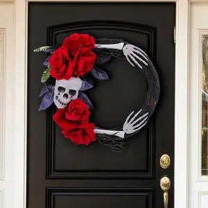 Couronne d'Halloween effrayante avec roses rouges, crâne et mains de squelette sur porte.