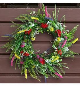Dettaglio di una ghirlanda di fiori selvatici artificiali su una porta di legno marrone