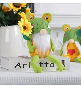 Simpatica bambola gnomo rana seduta su un libro bianco con un girasole