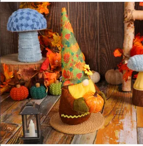 Close-up detail of a plush harvest festival gnome holding a pumpkin with an autumn leaf hat.