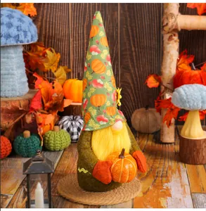 Detail of a plush harvest gnome holding a pumpkin for autumn holiday decoration.