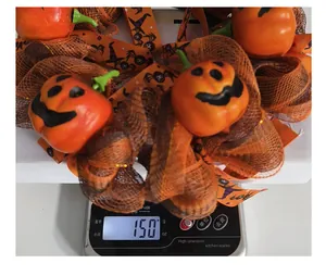 Nahaufnahme eines dekorativen Halloween-Kürbiskranzes auf einer Digitalwaage mit 150g