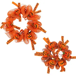 Festlicher Halloween-Kranz aus orangefarbenem Netz mit lächelnden Kürbisornamenten für die Tür