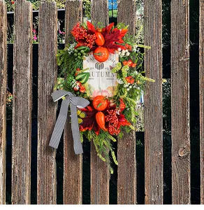 Detail van herfstkrans met neppompoenen en rustiek houten bord op een houten schutting