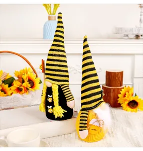 Macro view of handmade bee-themed faceless gnomes with striped hats and honey tag decoration