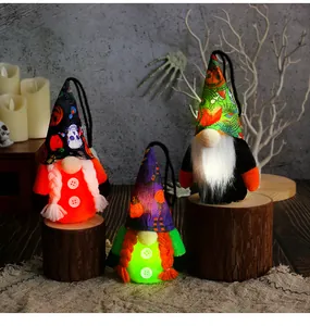 Three glowing Halloween gnome plush dolls with patterned hats on rustic wood stumps