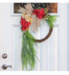 Rustic farmhouse floral wreath featuring red flowers and burlap bow on a white front door