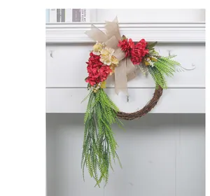 Rustic farmhouse flower wreath with red flowers and burlap bow on white wall decoration