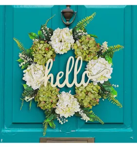 Dettaglio ghirlanda di ortensie artificiali con scritta 'hello' su porta color teal.