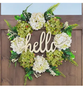 Dettaglio di ghirlanda di ortensie artificiali con scritta Hello in legno sulla porta.