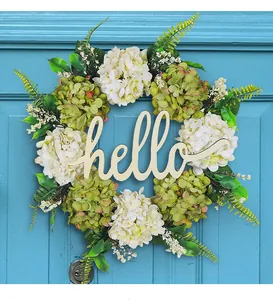 Primo piano di una ghirlanda di ortensie con scritta hello in legno su porta blu