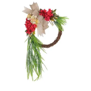 Handcrafted artificial floral wreath with red flowers and burlap bow for farmhouse door.