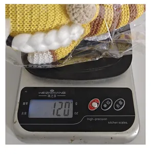Macro-detailweergave van een gebreide Bijenfestival-kabouterpop van 120 g op weegschaal