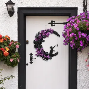 Gothic Halloween moon wreath with black roses and cat hanging on a white door