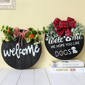 Two round wooden welcome signs with artificial greenery and festive plaid ribbons.