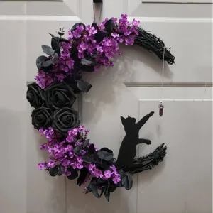 Detail view of a Halloween crescent moon wreath with black roses and a cat silhouette