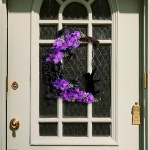Ghirlanda luna di Halloween con fiori viola e gatto nero su una porta bianca