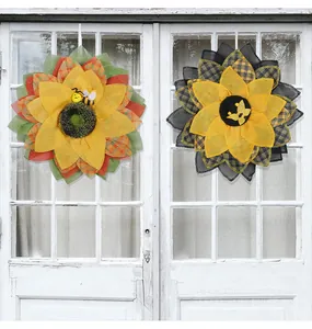 Détail des couronnes de tournesols jaunes avec abeilles sur une porte blanche rustique.