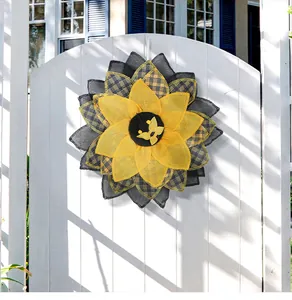 Couronne décorative de tournesol en toile de jute suspendue à un portail de jardin en bois blanc