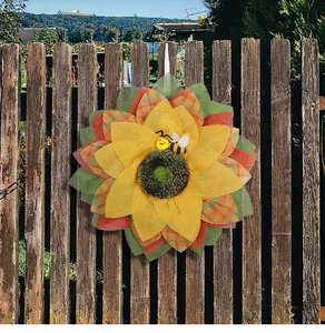 Couronne de tournesol et d'abeille artisanale sur une clôture en bois rustique de jardin.