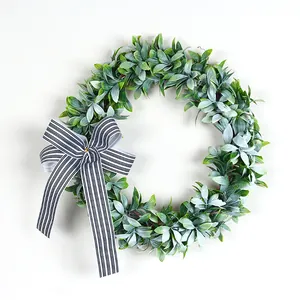 Close-up detail of artificial green leaf wreath featuring a black and white striped bow