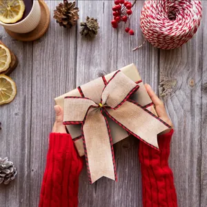 Burlap Christmas ribbon with red plaid edges used for elegant gift wrapping on wooden desk