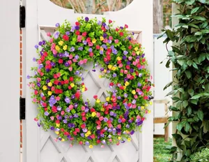 Couronne de fleurs artificielles multicolores sur une porte de jardin blanche élégante.