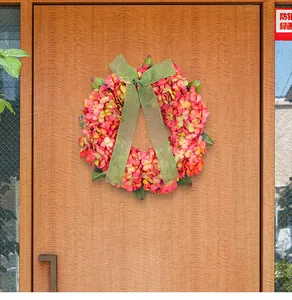 Dettaglio di una ghirlanda di ortensie autunnali artificiali con nastro verde sulla porta