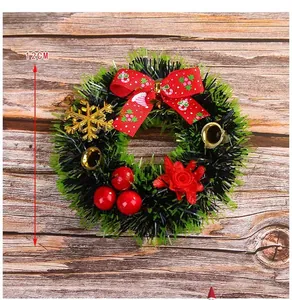Detail view of 12cm Christmas wreath with red bow, gold bells, and berries on wood background