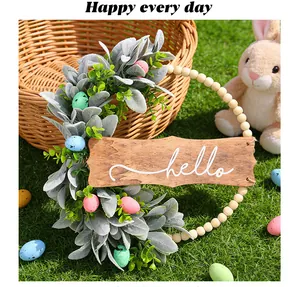 Close-up of Easter wreath with rabbit ear leaves, colorful eggs and hello sign.