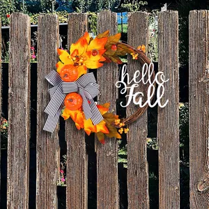 Decorative autumn wreath featuring maple leaves and Hello Fall sign on a rustic fence