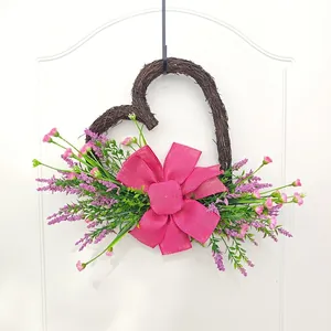 Heart-shaped hand-woven twig wreath with pink artificial flowers and large pink bow.