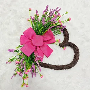 Close-up of a heart-shaped grapevine wreath with pink burlap bow and artificial flowers