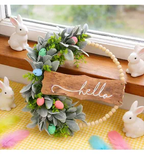 Decorative Easter wreath with 'hello' wooden sign and colorful eggs on window sill