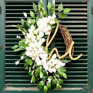 Handgefertigter Frühlingskranz mit weißen Tulpen und Holzmonogramm an grüner Jalousie