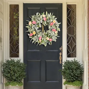 Corona de oreja de cordero con rosas rosas y amarillas en una puerta de entrada negra